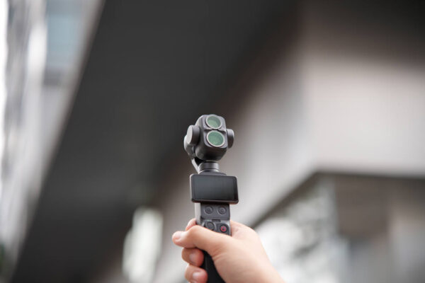 DJI Osmo Pocket 4 Pro med NiSi-filter hålls upp utomhus mellan husen
