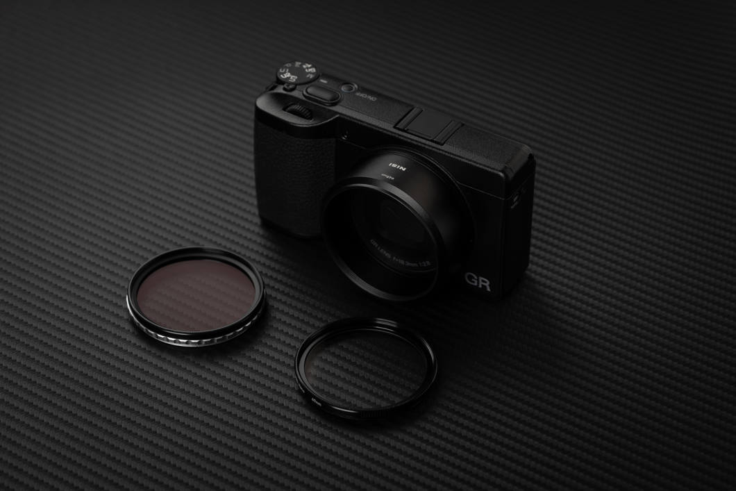 Ricoh GR IV med NiSis 49 mm-adapter, två runda filter ligger framför kameran