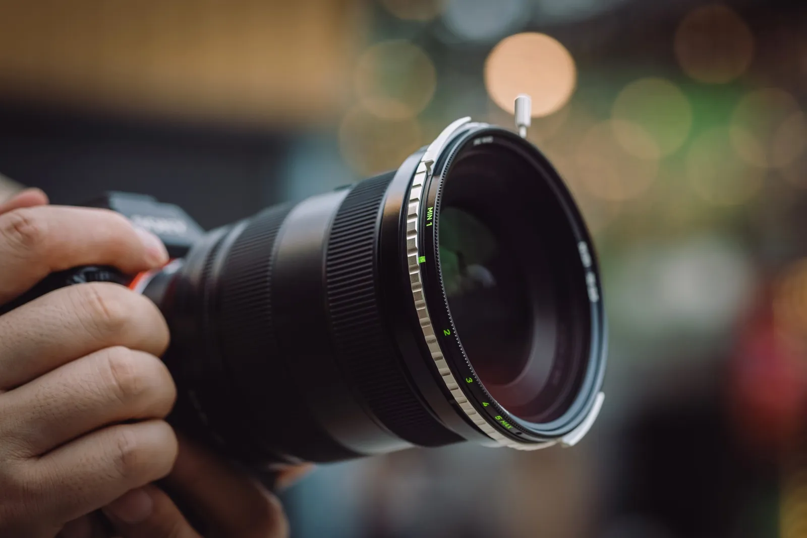 Hand vrider styrkan på ett NiSi variabelt ND-filter som sitter på objektivet